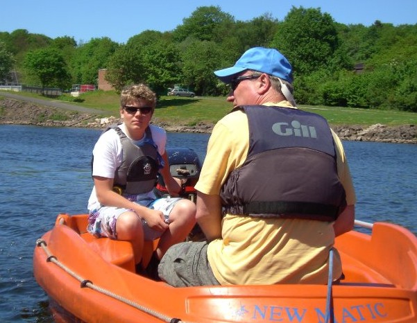 Sailing instructors in an orange powerboat keeping watch over beginner sailors